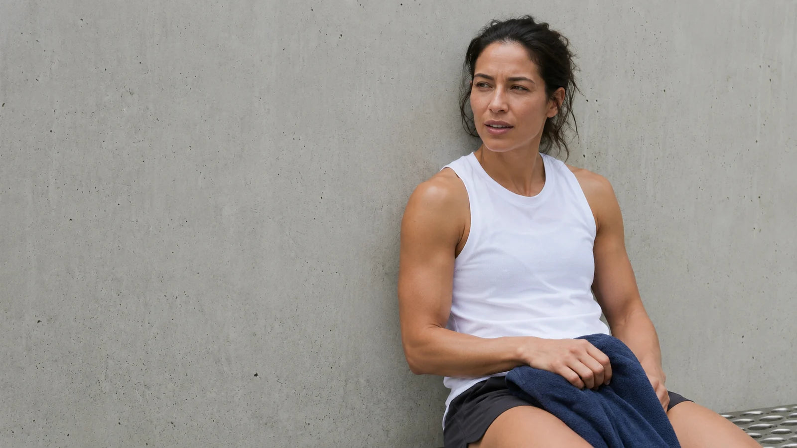 Woman taking a break after training by a concrete wall